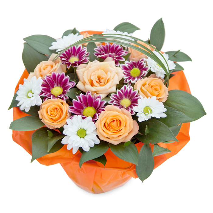 Expertly styled by the skilled hands of Flowers Ardleigh Green, this vivid bouquet is photographed from an elevated vantage, highlighting a harmonious blend of nature's finest colours and textures-tailored for events or everyday moments across Ardleigh Green and Gidea Park. The arrangement's centerpiece features expanses of peach and orange roses, their petals velvet-smooth and gently unfurling, each bloom basking in the serene light reminiscent of nearby parks. Interspersed among these, a parade of chrysanthemums offers visual variety: white petals with lively green centers echo the freshness of morning dew, while magenta-purple blooms with vibrant green hearts provide dramatic contrast and intrigue. The composition is enhanced by lush, glossy dark green foliage, likely ruscus, which offers both depth and a grounding, forest-like quality, inspired by Ardleigh Green's own leafy surroundings. Above the arrangement, an elegant thread of bear grass curves in a delicate arc, introducing movement and an airy sophistication to the design. At the base, the bouquet is wrapped in crinkled, bright orange cellophane-its playful texture and bold colour highlighting the warmth of the roses and welcoming the eye with a sense of joy. Every detail in this bouquet showcases the artistry and local expertise of Ardleigh Green florists, producing a floral gift as memorable as it is beautiful.